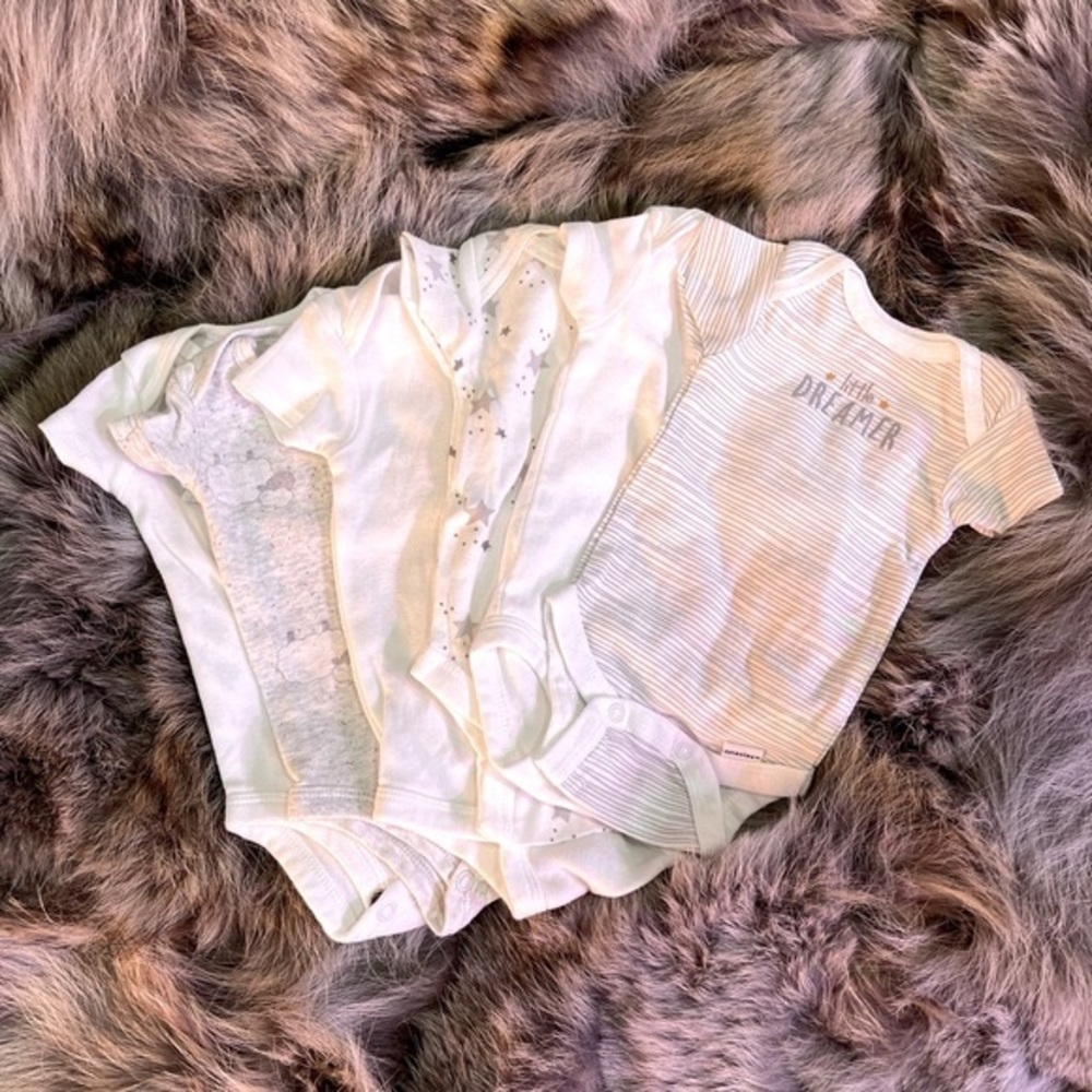 Three patterned Carter’s and three solid white Gerber’s onzies